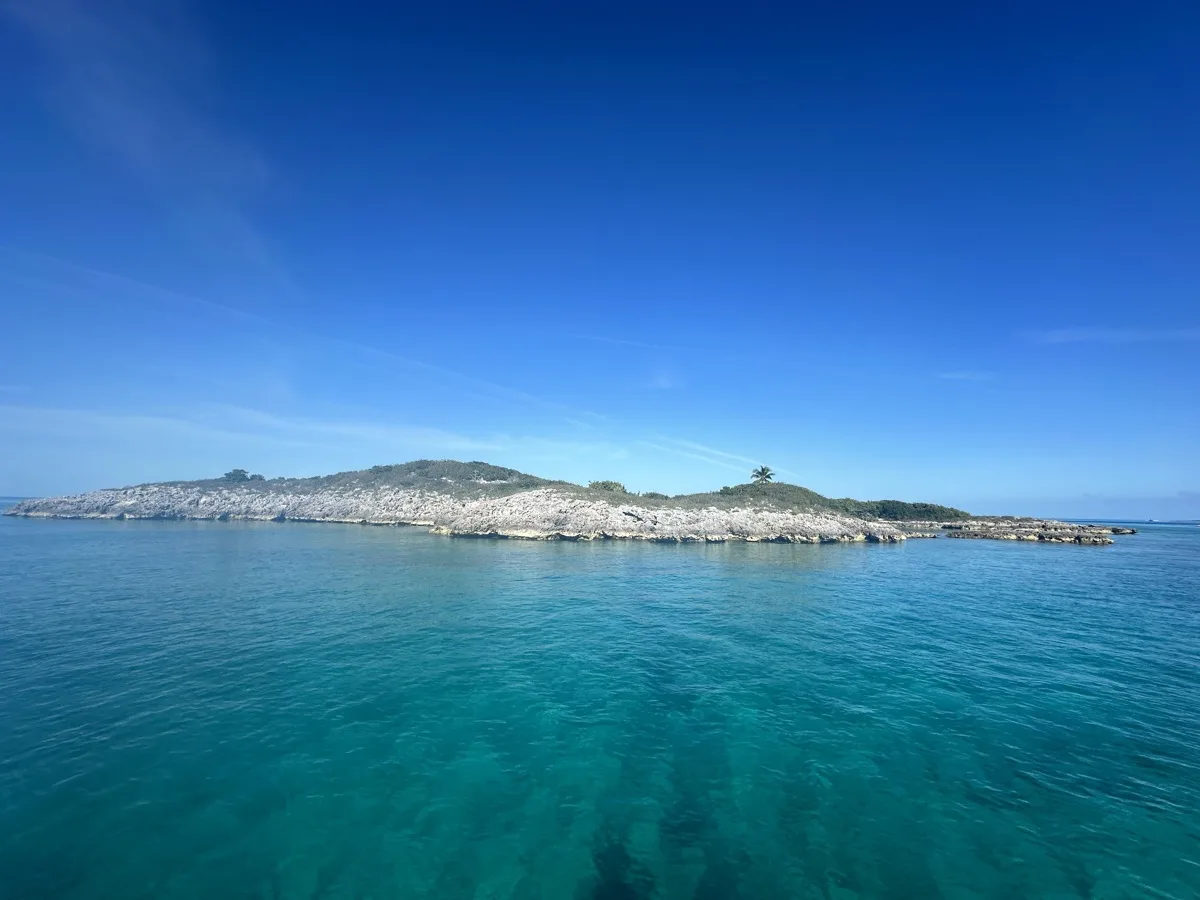 Rocky limestone cay rising from clear turquoise water in the Exuma Cays, the same formation type as Thunderball Grotto near Staniel Cay