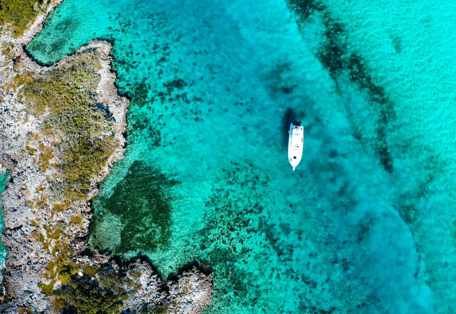 Small boat on turquoise Bahamas water seen from above